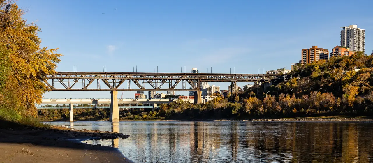 The High Level Bridge spanning the North Saskatchewan River with autumn trees reflected in the water